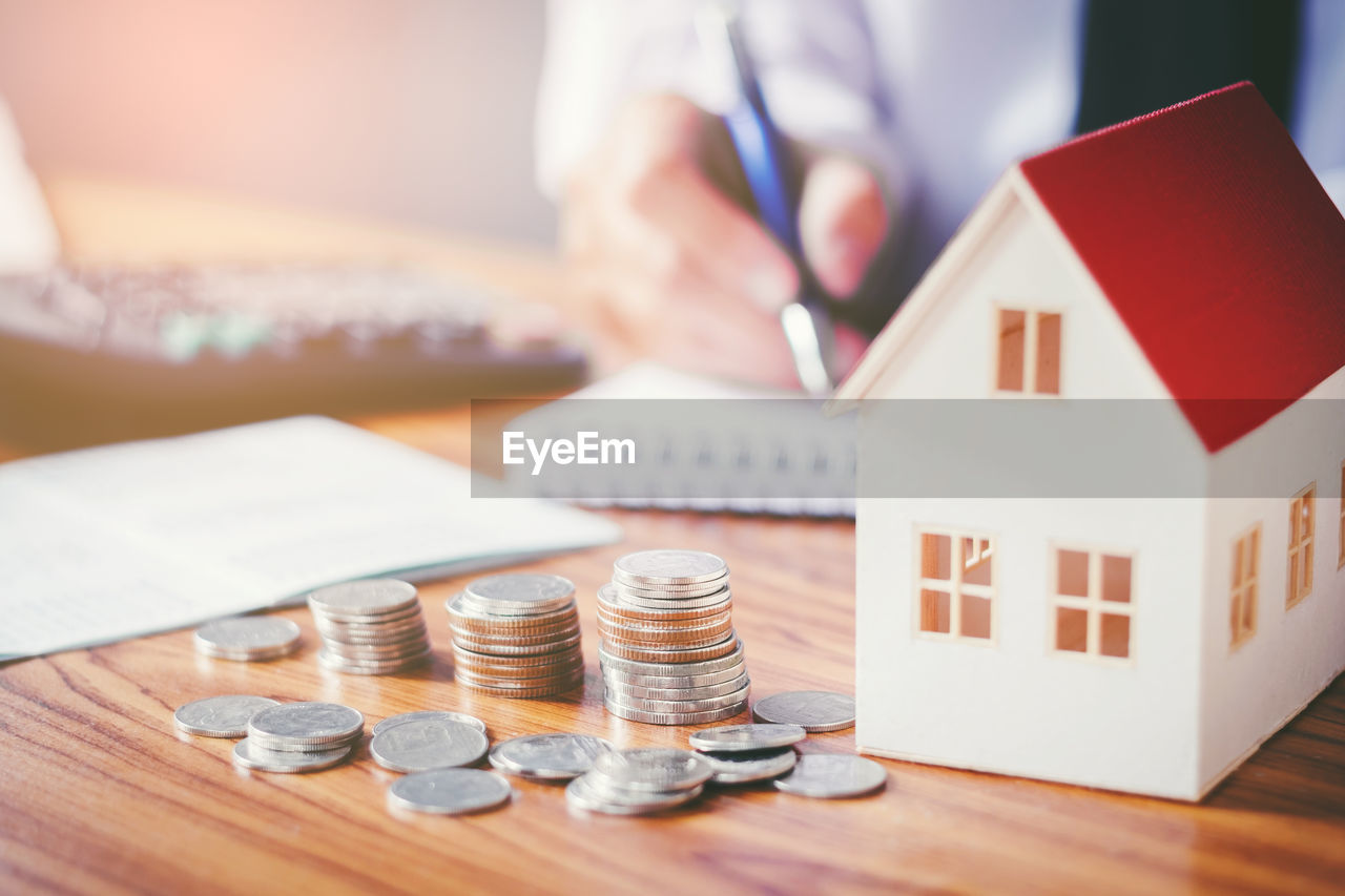 Close-up of coins and model house on table