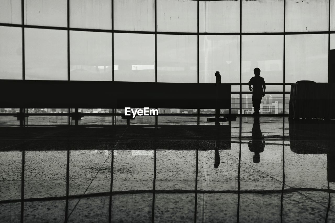 Silhouette boy standing by window at airport