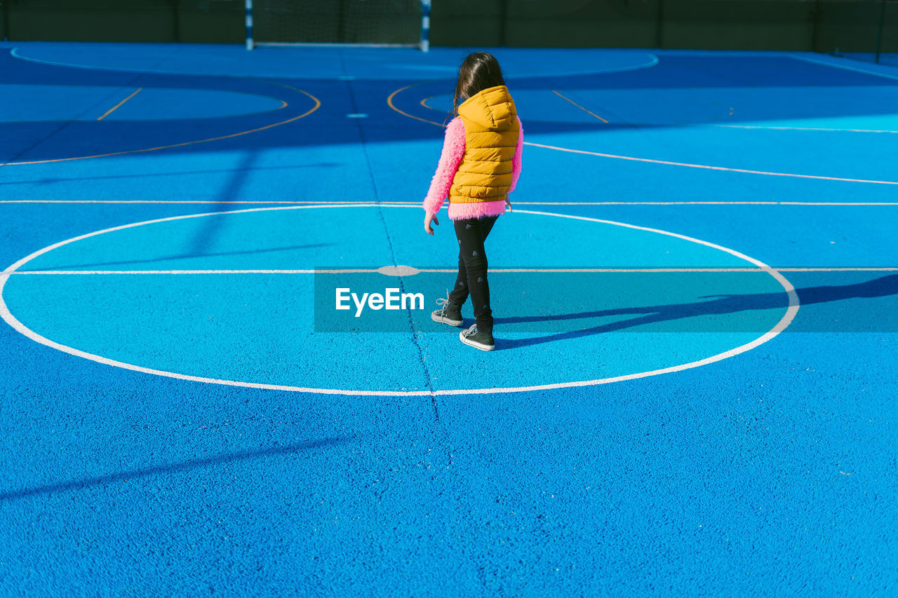 Girl in warm clothing standing on soccer court during sunny day