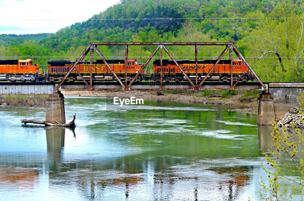 Freight train on bridge over river against sky