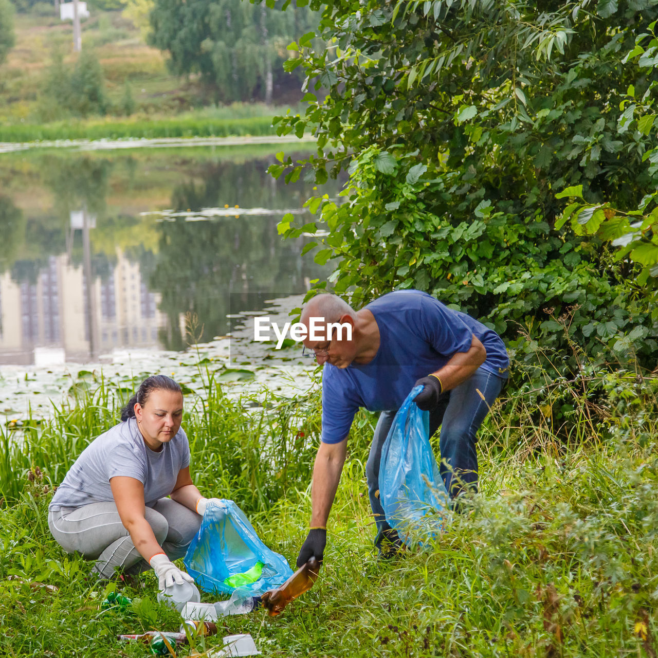Couple collecting garbage by lake