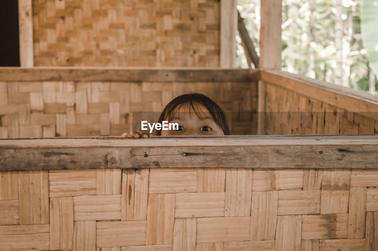 Portrait of girl hiding behind retaining wall