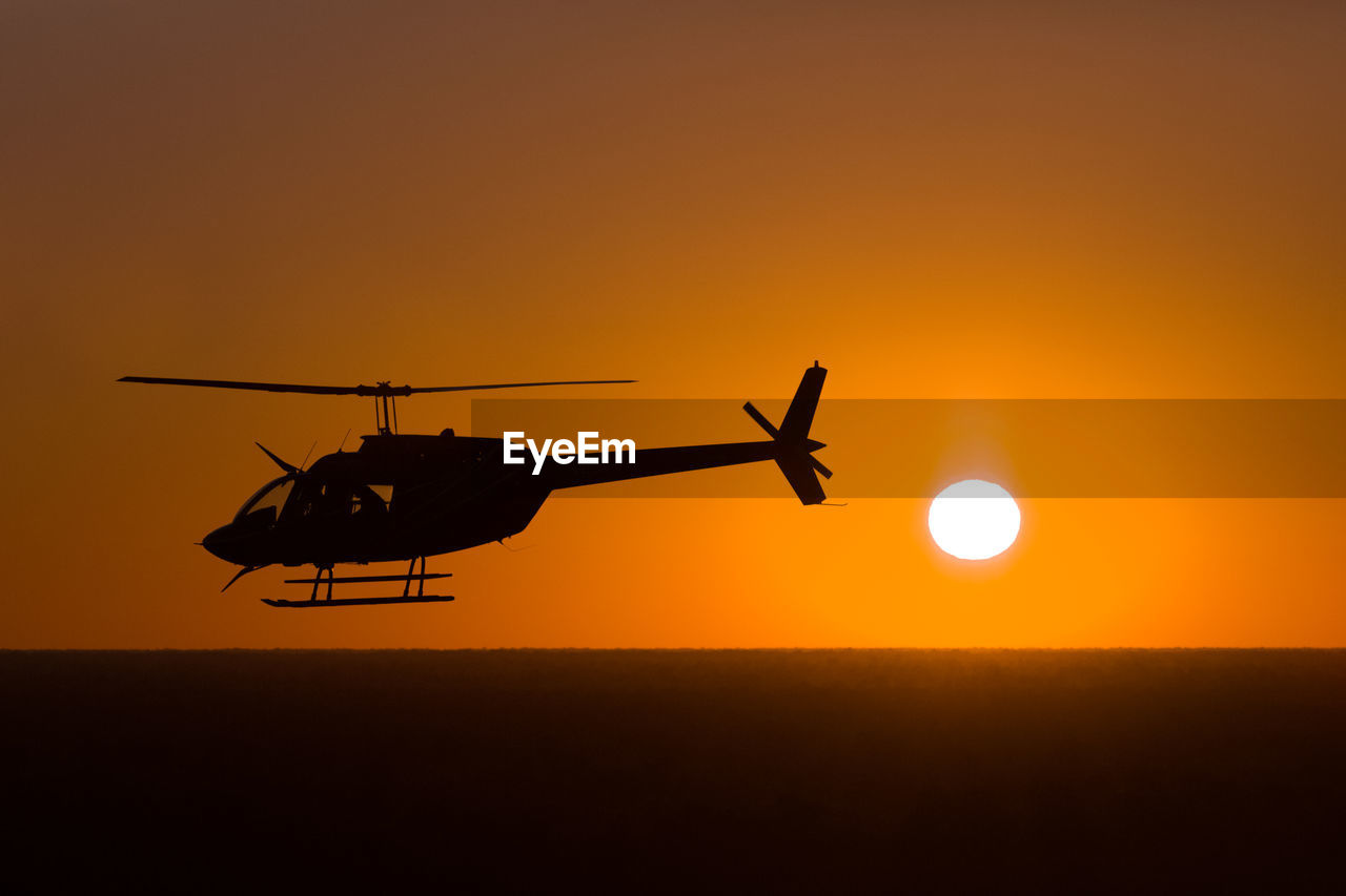 Helicopter flying on sunset background