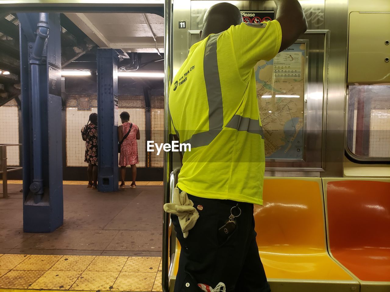 REAR VIEW OF MEN STANDING ON TRAIN AT SUBWAY STATION