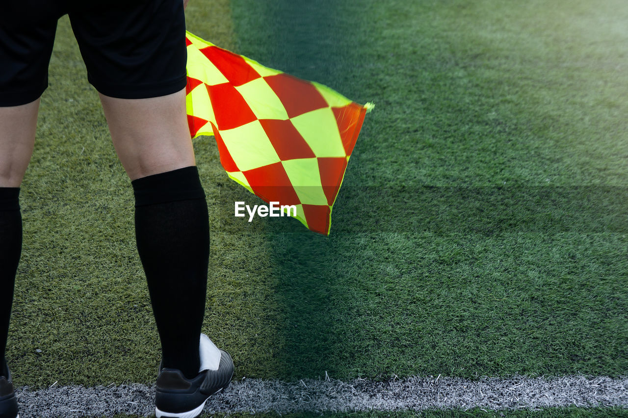 Low section of man with flag standing on soccer field