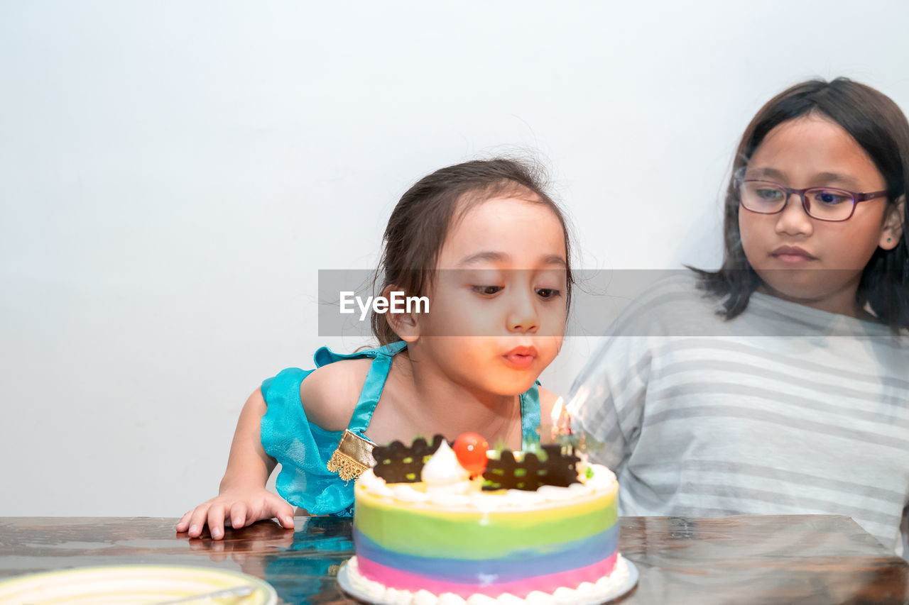 Little girl is blowing candles on her birthday cake. celebrating at home during quarantine.