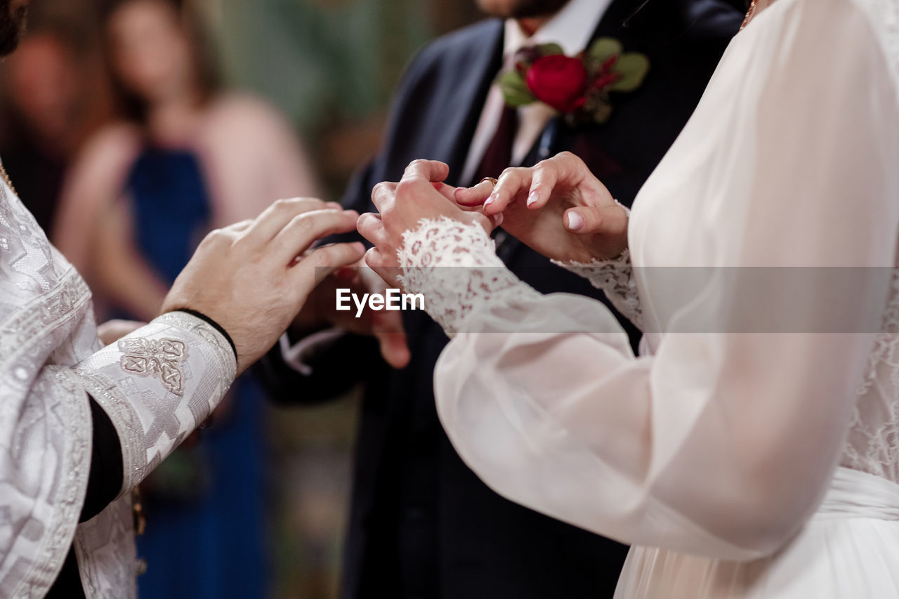 midsection of bride and bridegroom holding hands