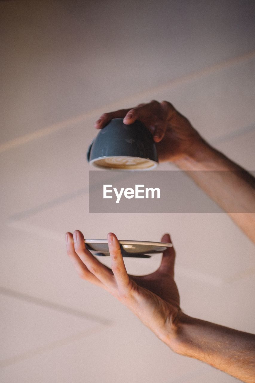 Close-up of hand holding coffee cup upside down