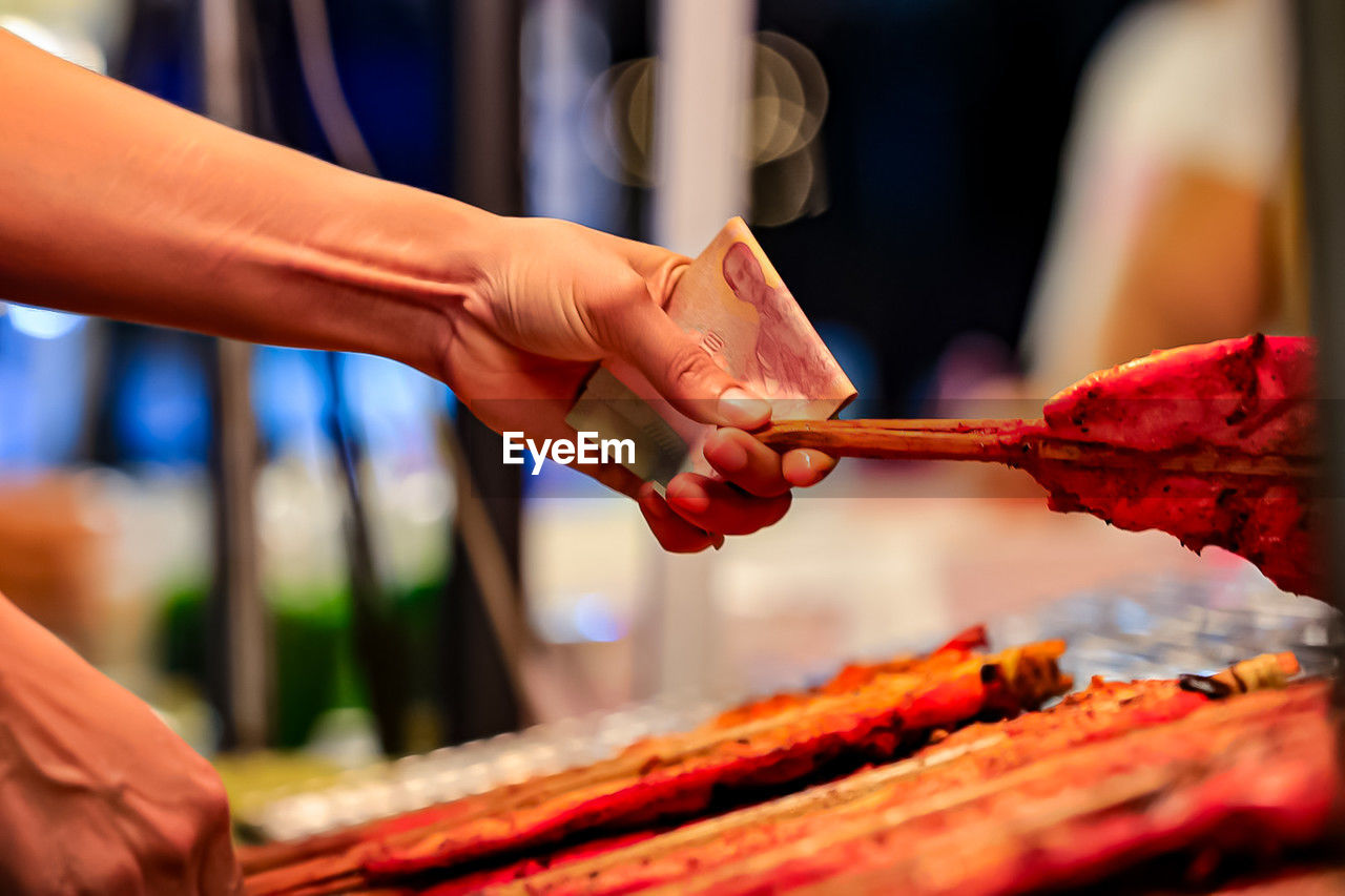 hand, food and drink, adult, food, red, business, retail, meat, two people, market, women, selective focus, celebration, freshness, business finance and industry, close-up, bottle, holding, men, customer