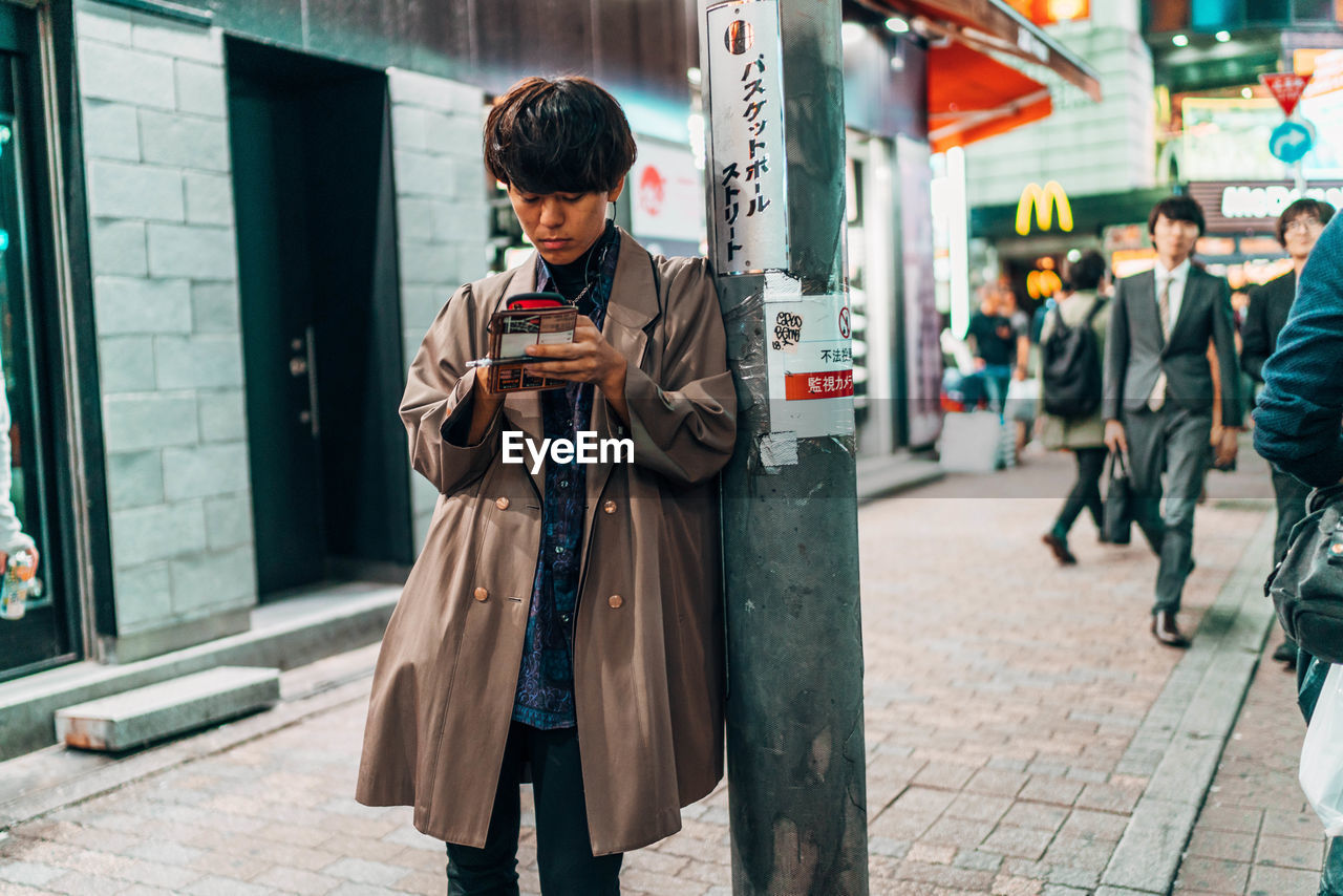 FULL LENGTH OF MAN USING MOBILE PHONE ON STREET