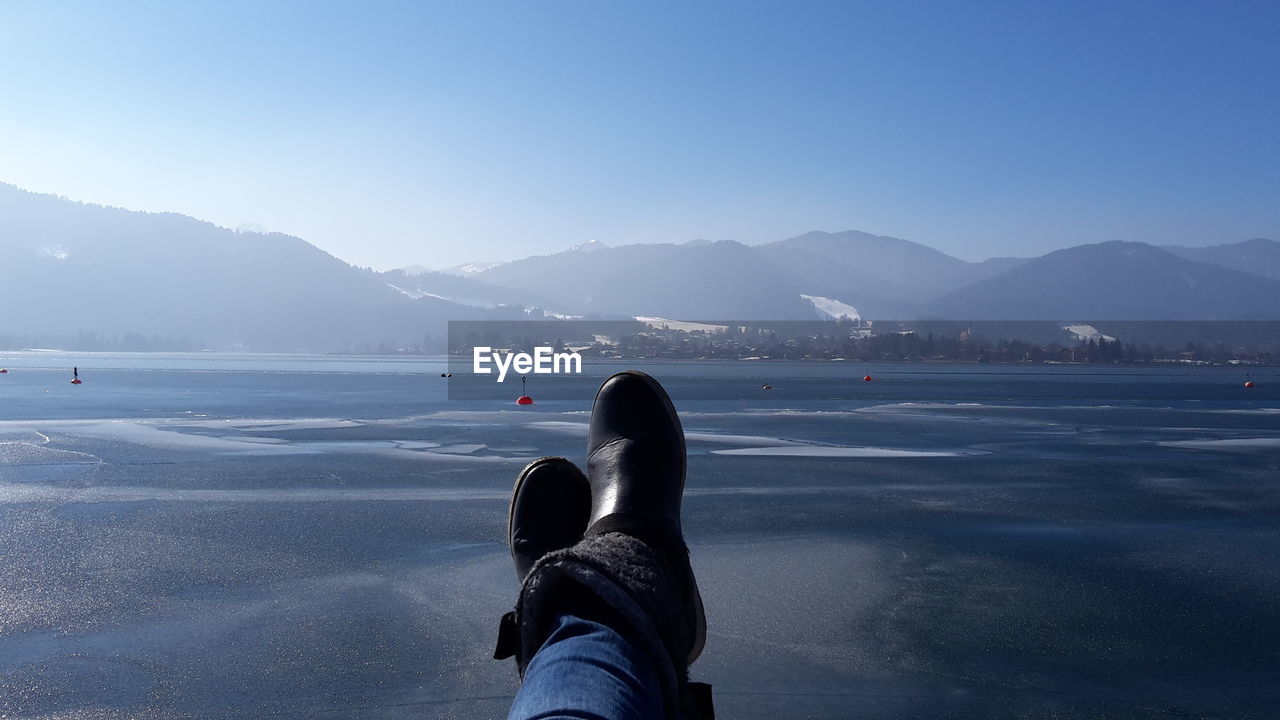 Low section of woman wearing shoes against mountain range