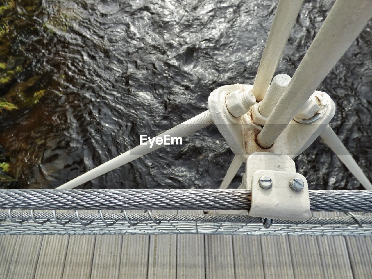 High angle view of steel cables and metal on suspension bridge over river