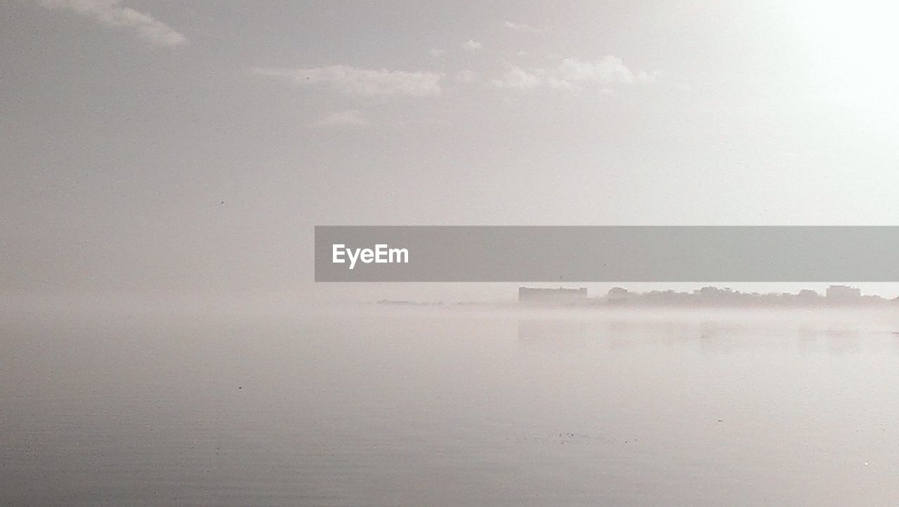 Scenic view of calm lake in foggy weather against sky