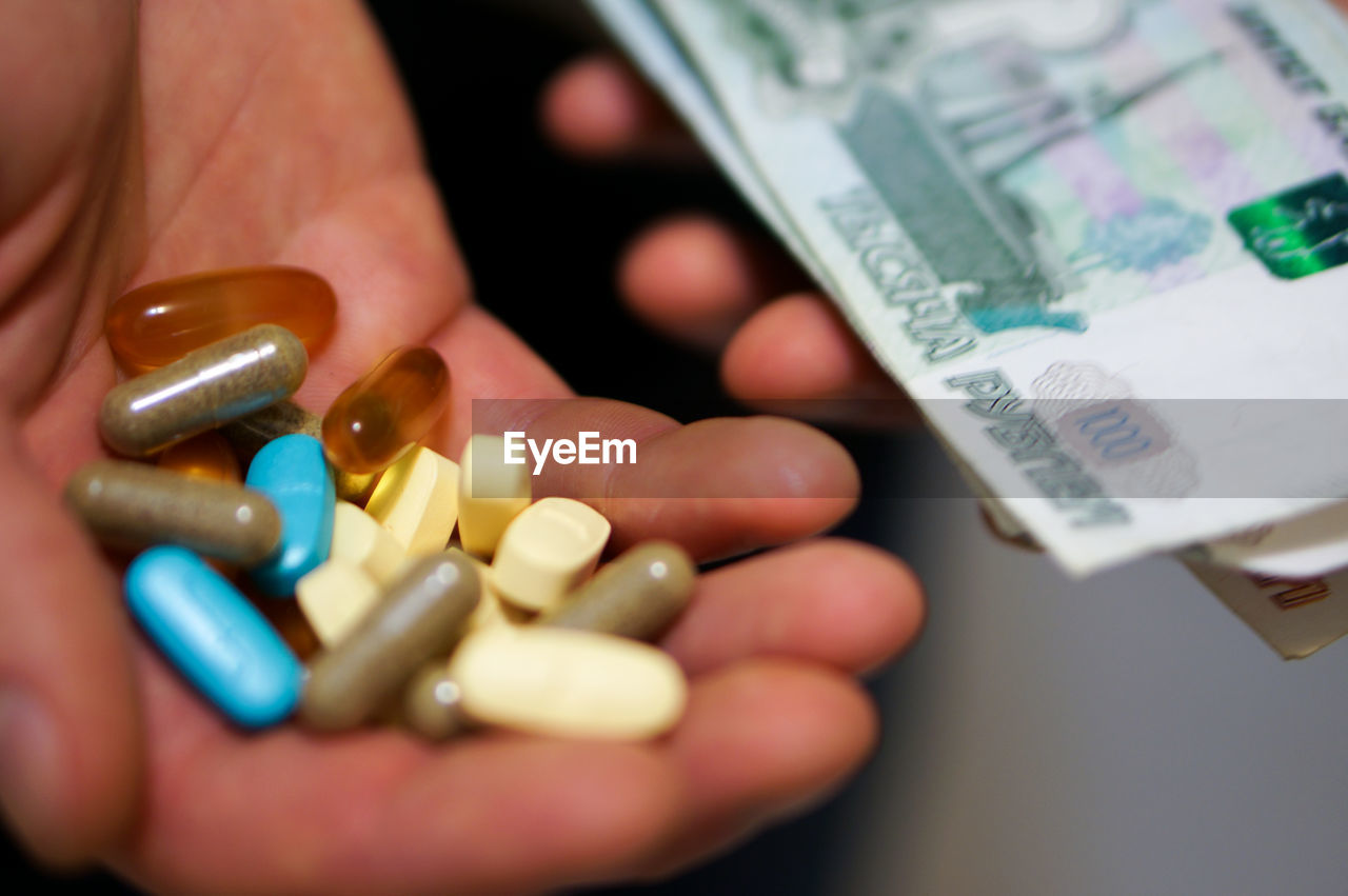 Close-up of hand with pills and money