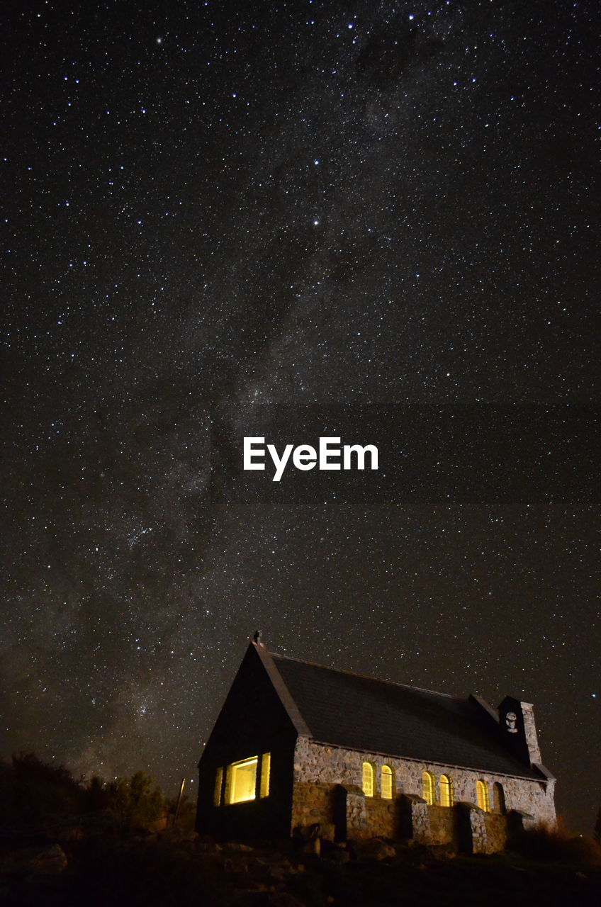 LOW ANGLE VIEW OF ILLUMINATED BUILDING AGAINST STAR FIELD