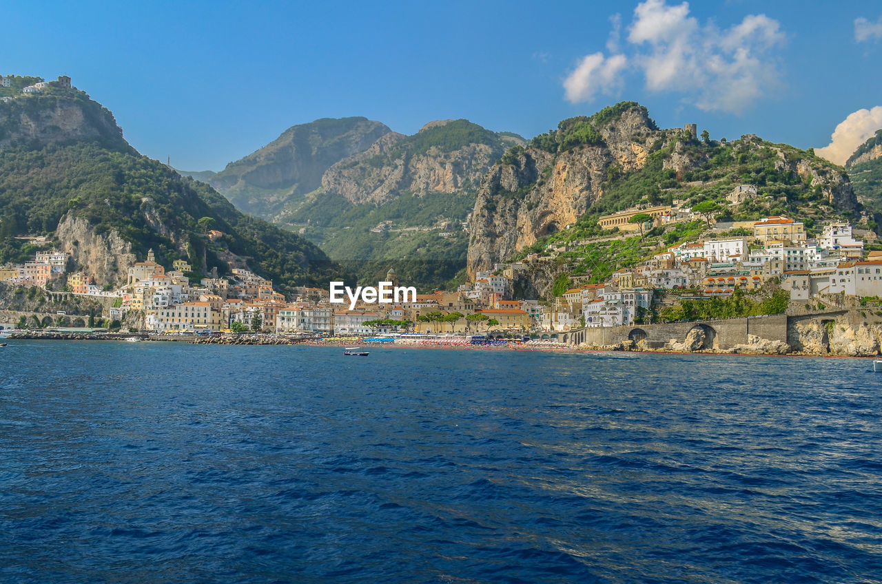 Town by sea and mountains against sky