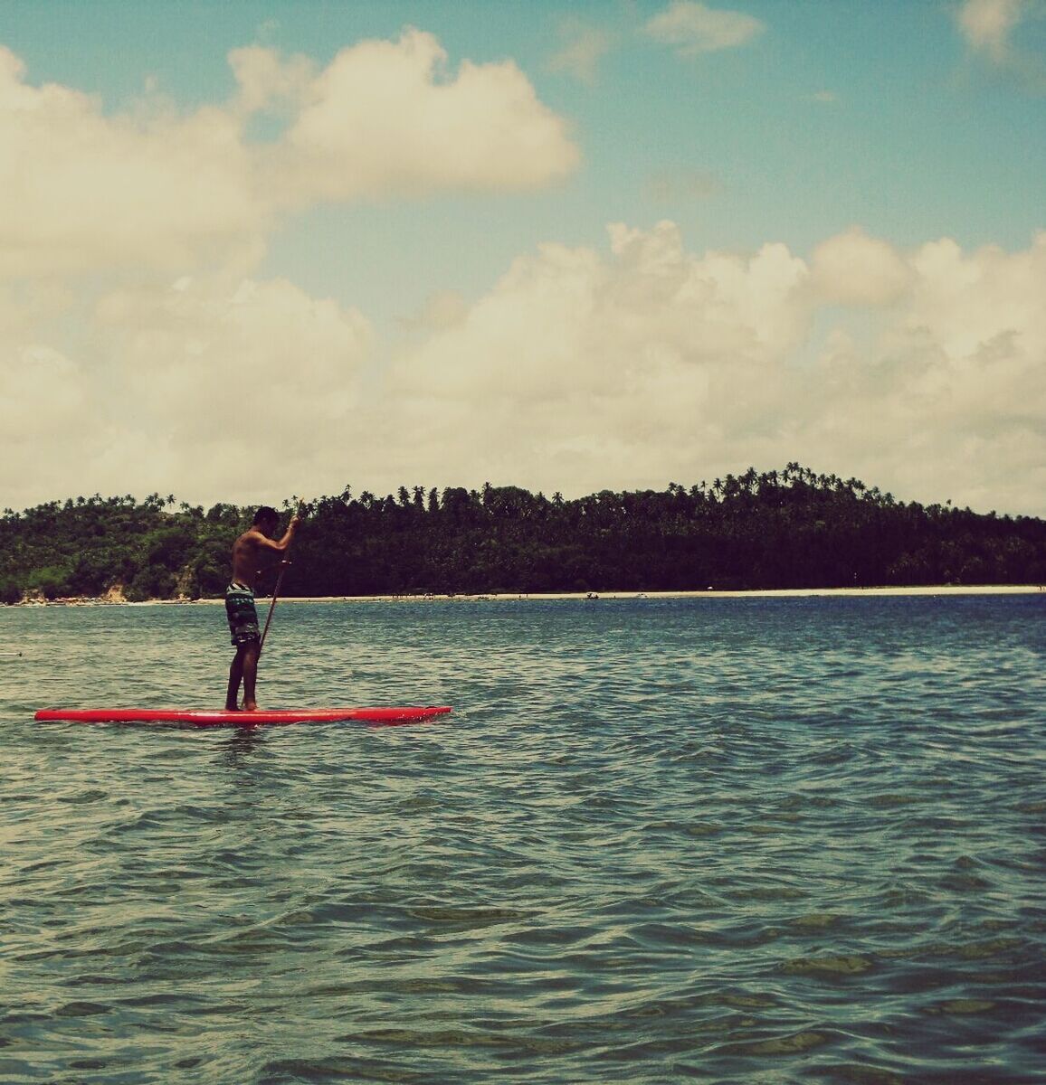 Man paddleboarding on lake against cloudy sky