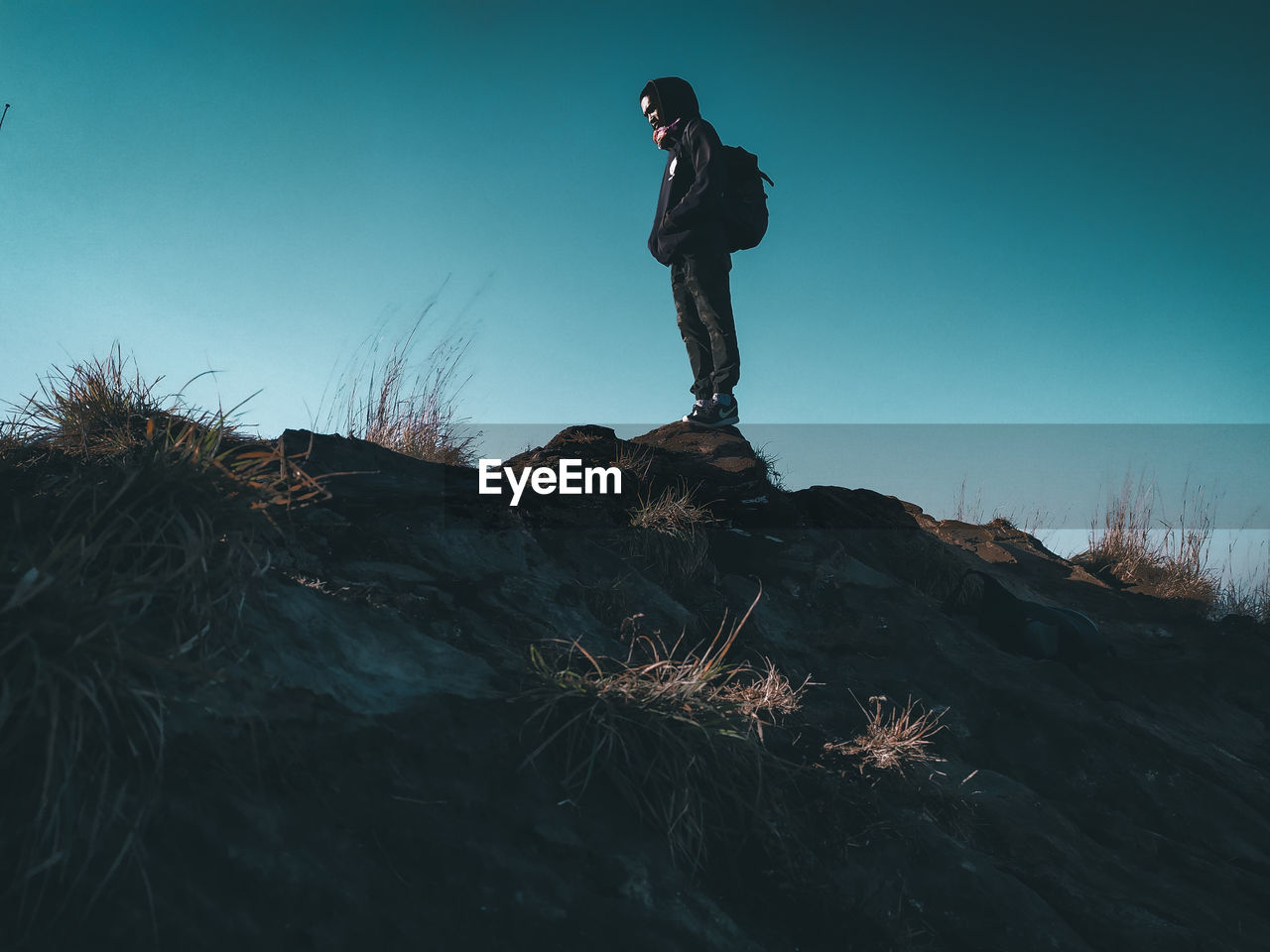 Low angle view of man standing on rock against sky