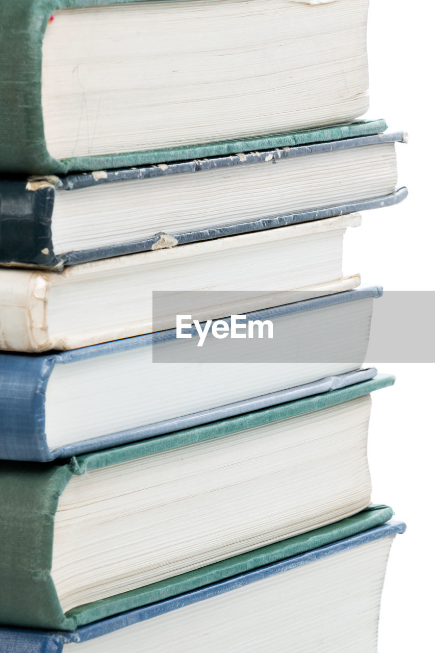 Close-up of books stacked on table against white background