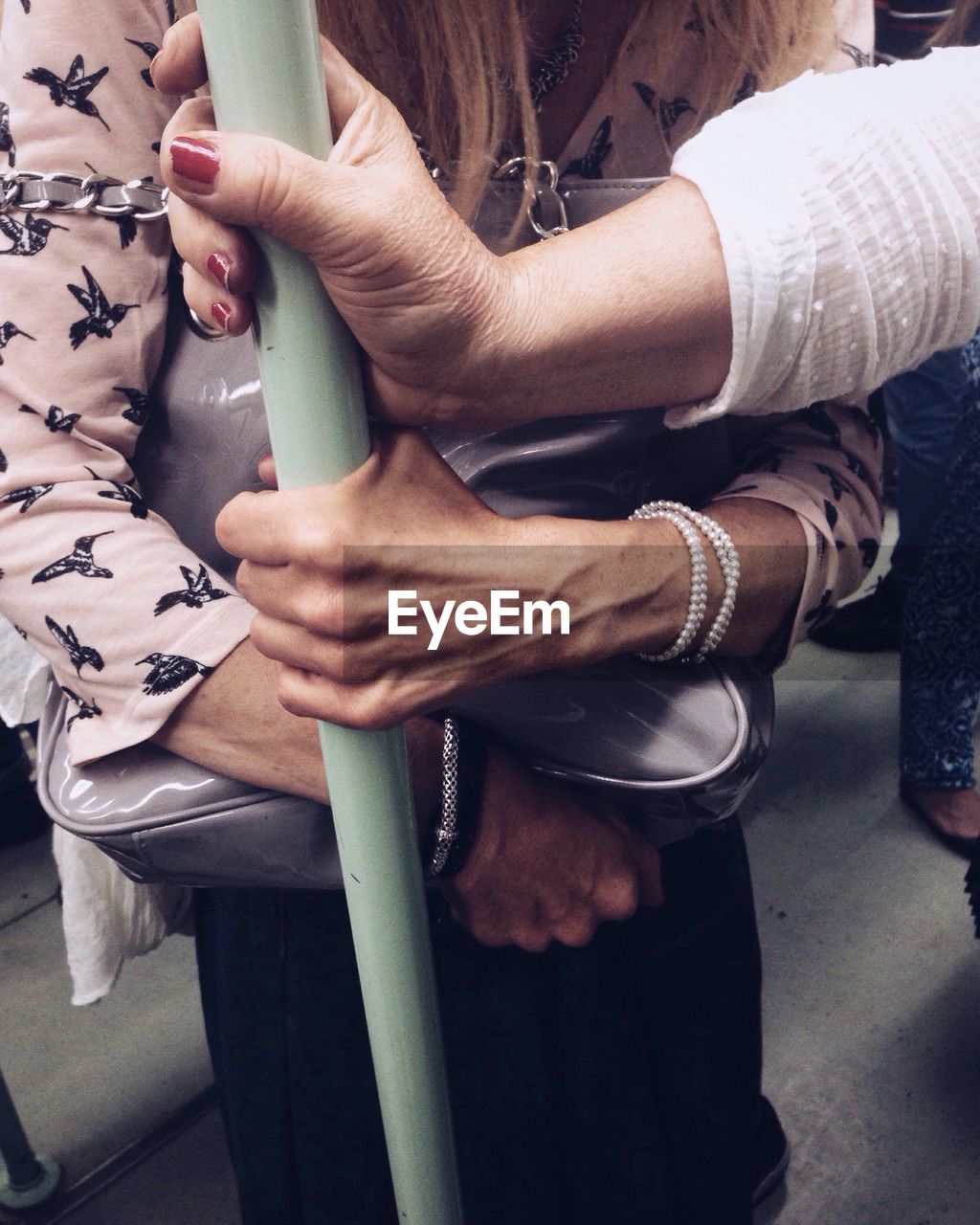 Midsection of women holding pole in train
