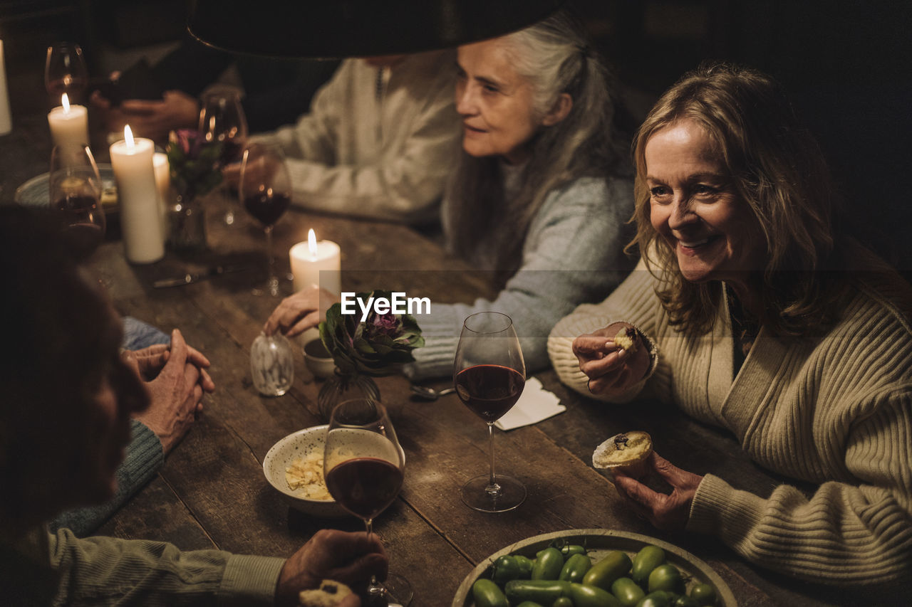 Smiling senior woman eating cupcake while talking to friend during party