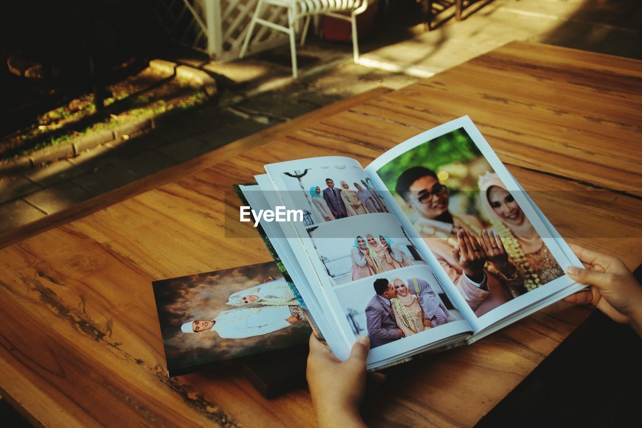 Hands of person holding photo album at table