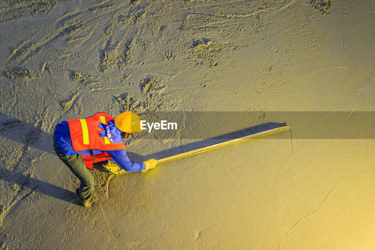 HIGH ANGLE VIEW OF MAN WORKING ON SAND AT BEACH