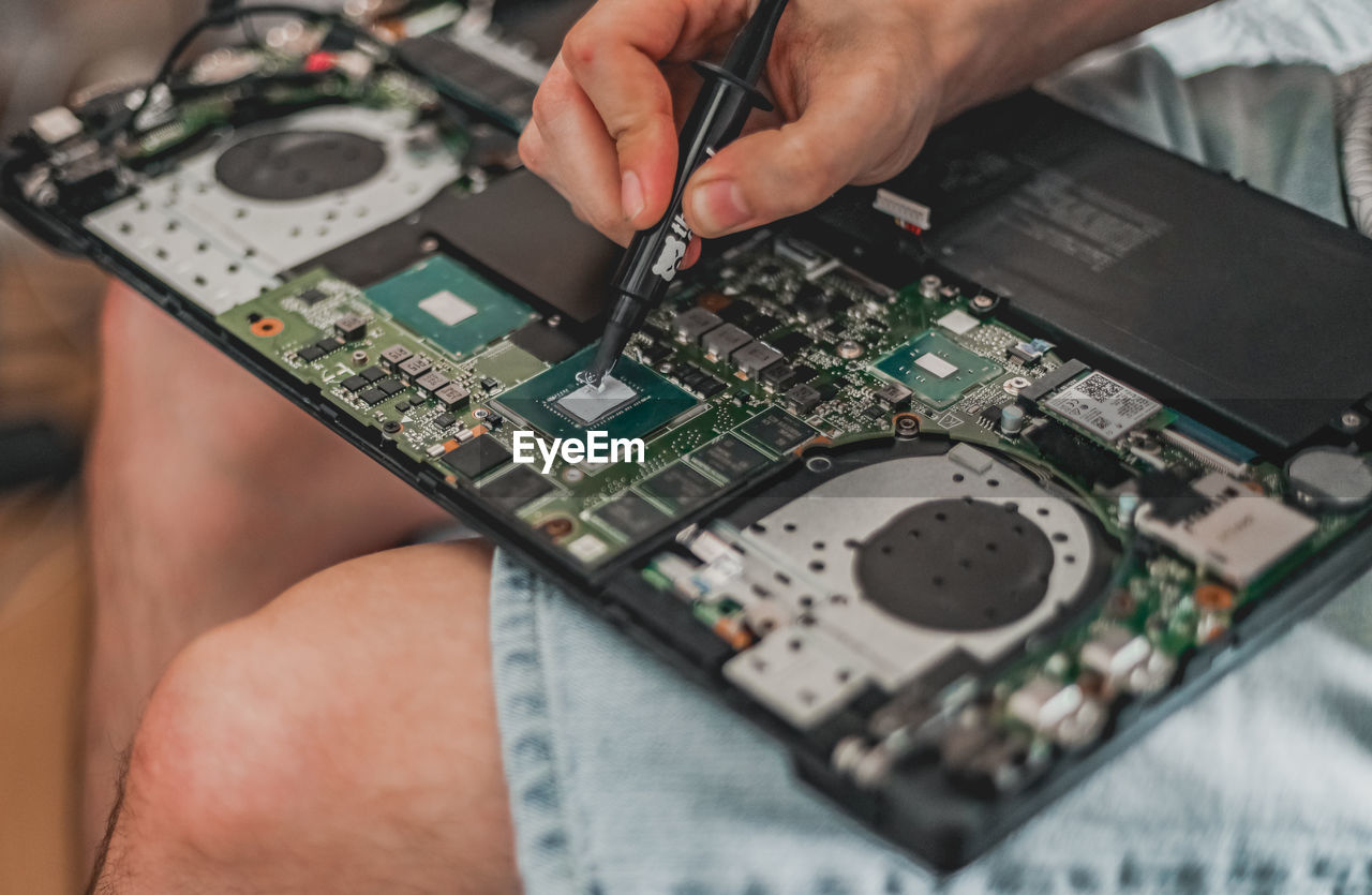 A young man is changing the thermal paste on a laptop.