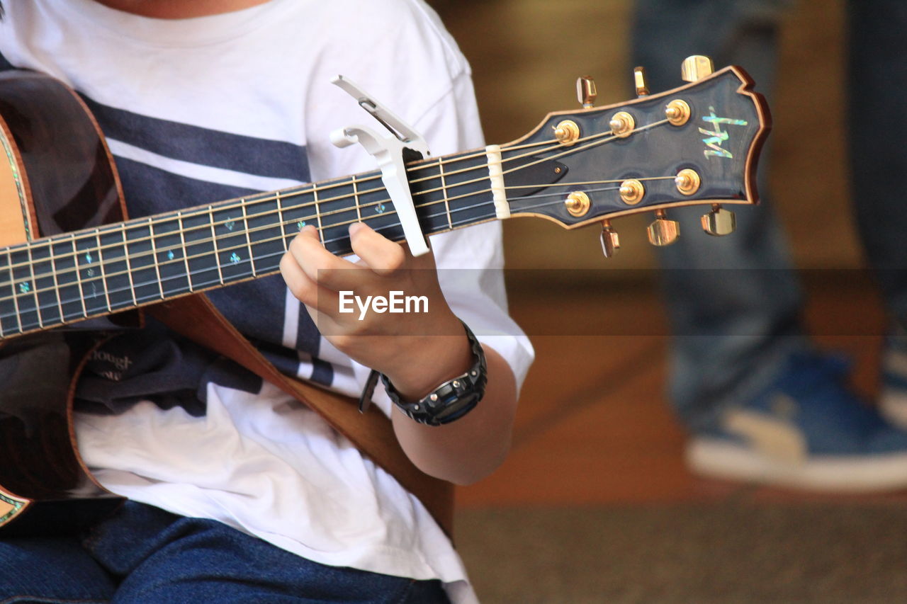 CLOSE-UP OF MAN PLAYING GUITAR ON STAGE