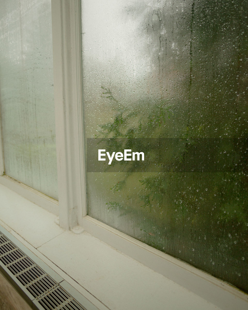 CLOSE-UP OF WET GLASS WINDOW AGAINST WALL