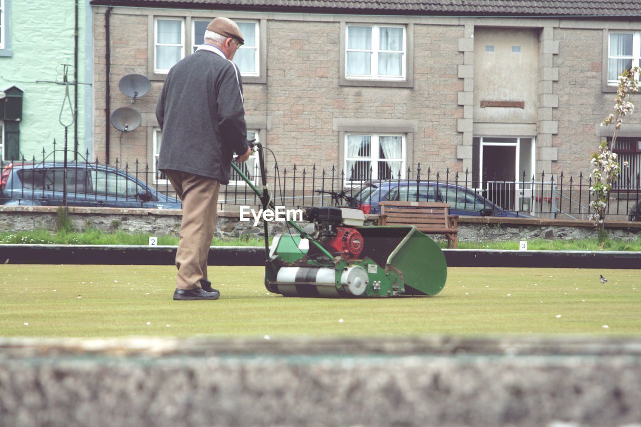 Man working on bowling green mowing the grass