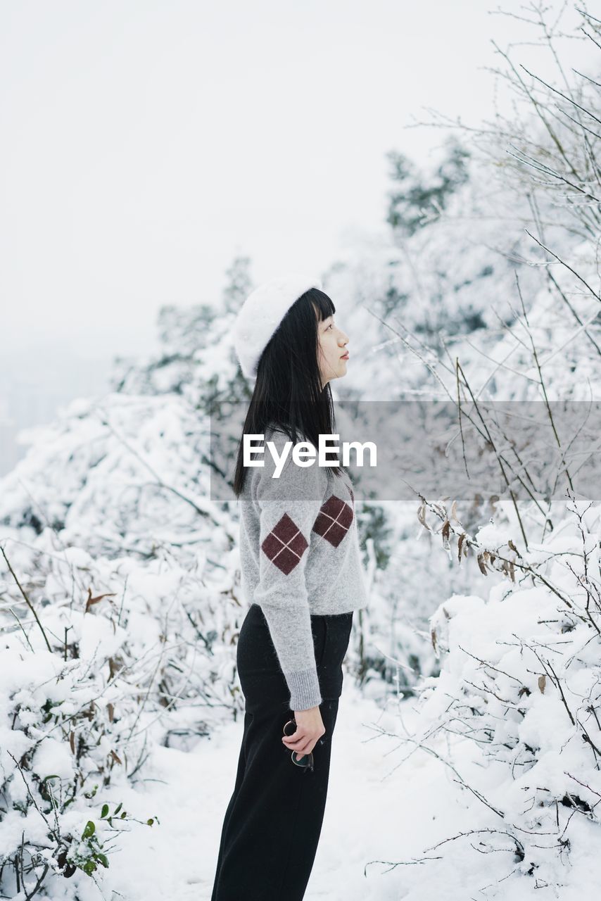 Woman standing on snow against sky