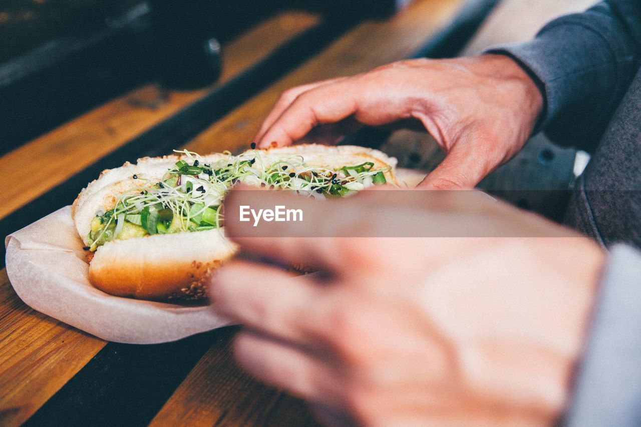 Cropped image of man eating hot dog