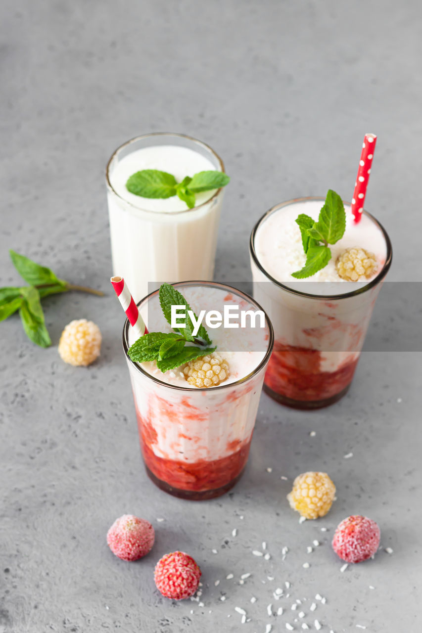 Layered strawberry and raspberry smoothie or milkshake with mint, raspberry and coconut flakes. 