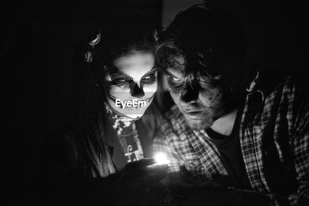 Friends with spooky make-up in darkroom during halloween