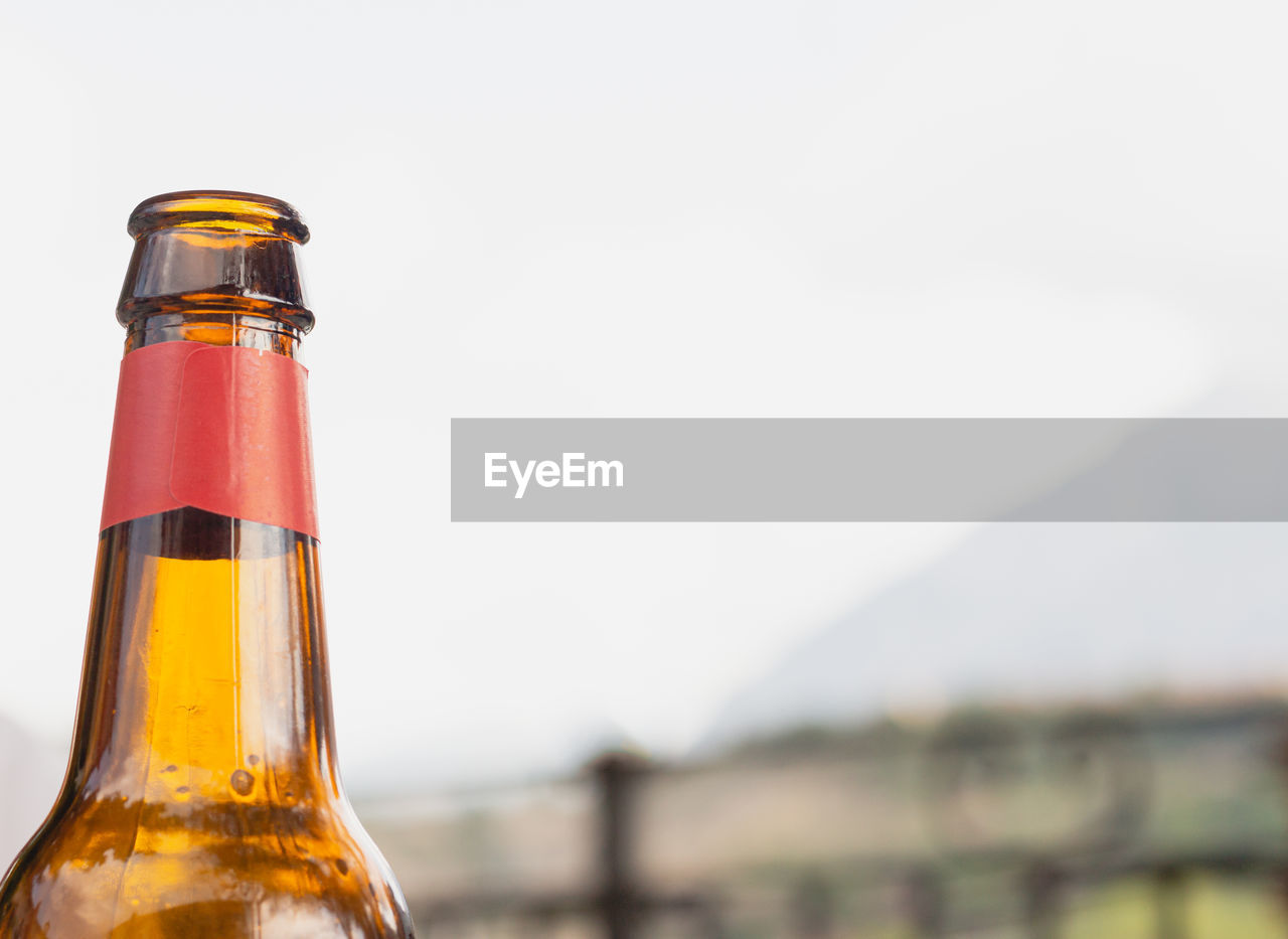 bottle, container, alcohol, drink, refreshment, food and drink, beer, glass, focus on foreground, drinkware, sky, alcoholic beverage, close-up, no people, copy space, drinking glass, nature, water, single object, wet, cold temperature, household equipment, glass bottle, still life, yellow, beer glass, outdoors