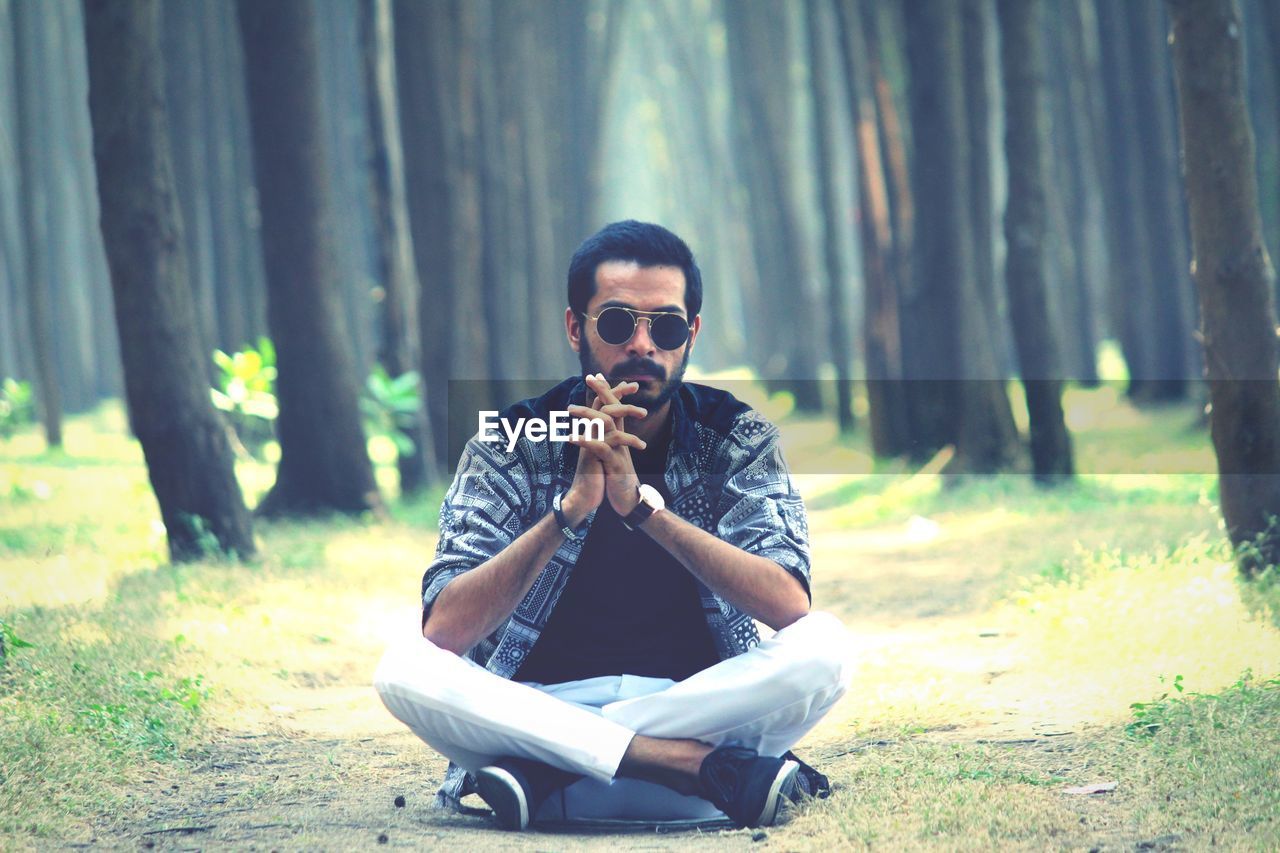 Portrait of serious young man sitting in forest