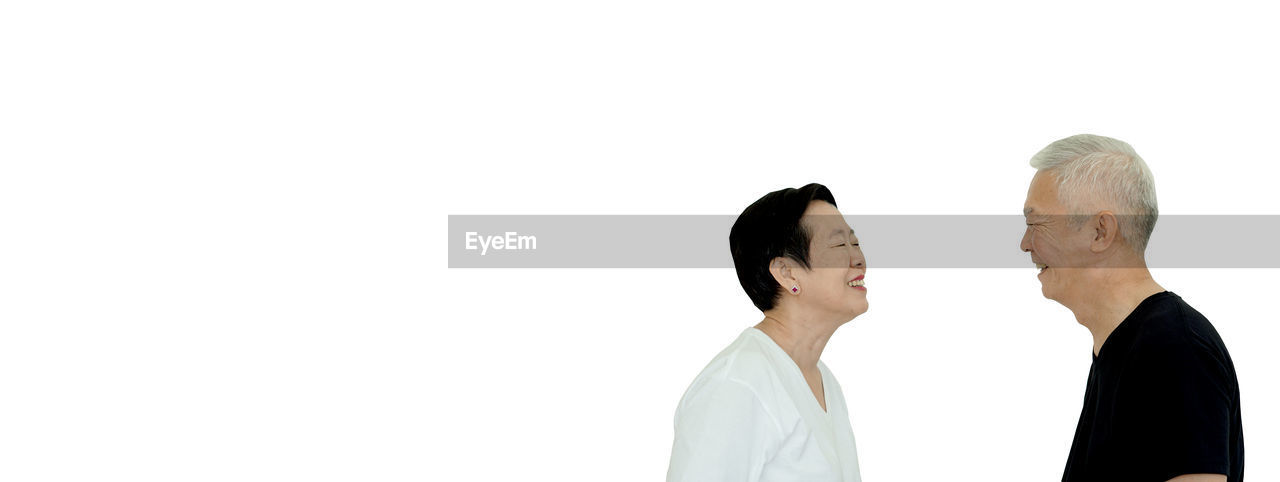 SIDE VIEW OF TWO PEOPLE LOOKING OVER WHITE BACKGROUND