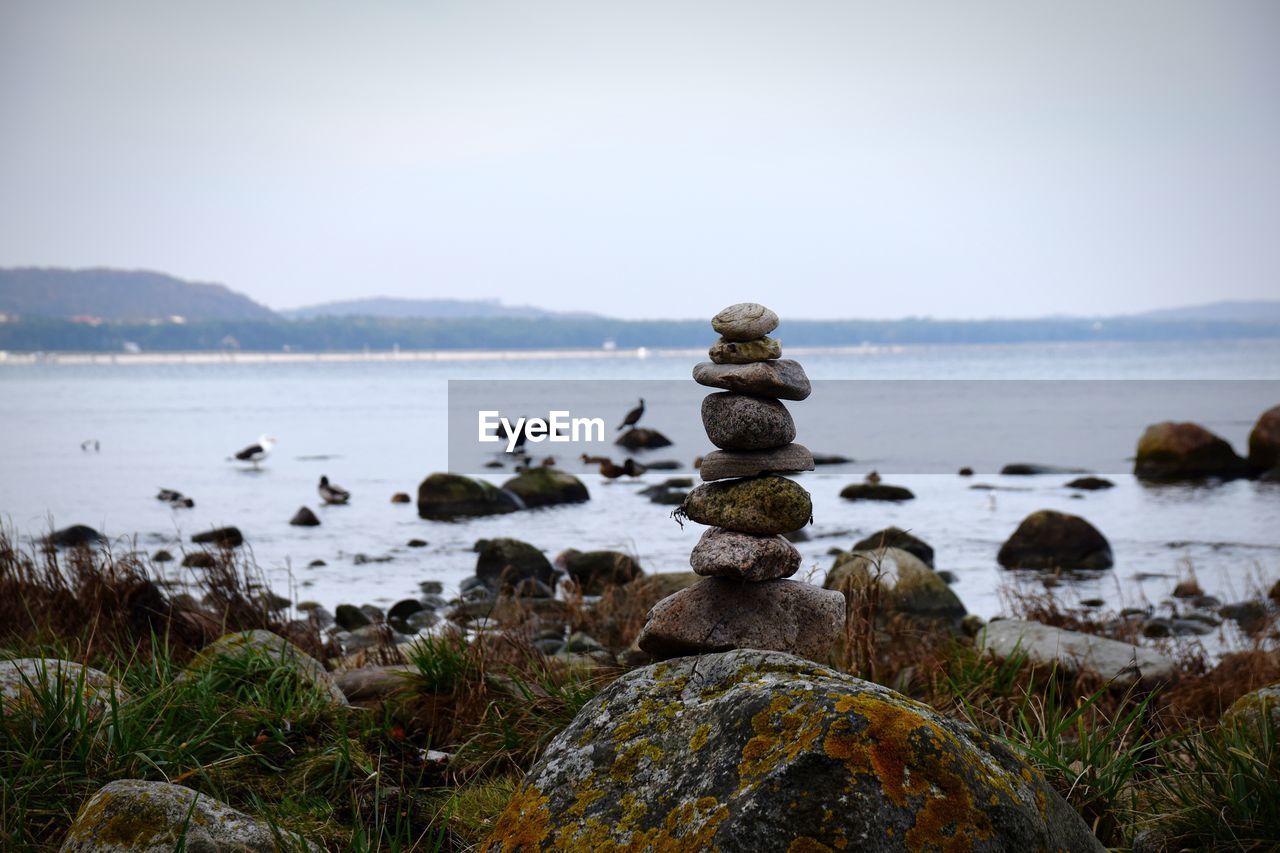 STACK OF STONES ON SHORE AGAINST SKY