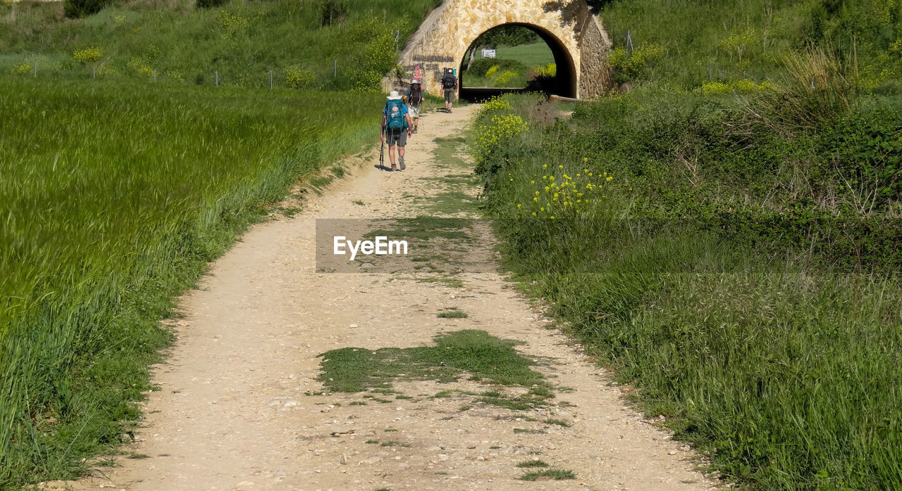 PEOPLE WALKING ON DIRT ROAD