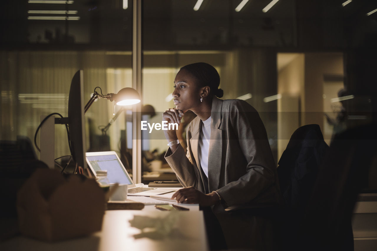 Businesswoman concentrating while working on computer overtime at work place