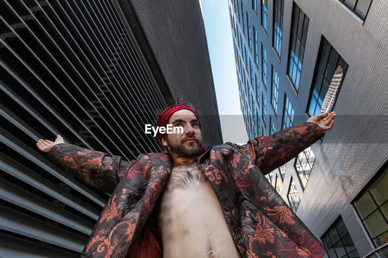 Low angle view of shirtless man standing amidst buildings