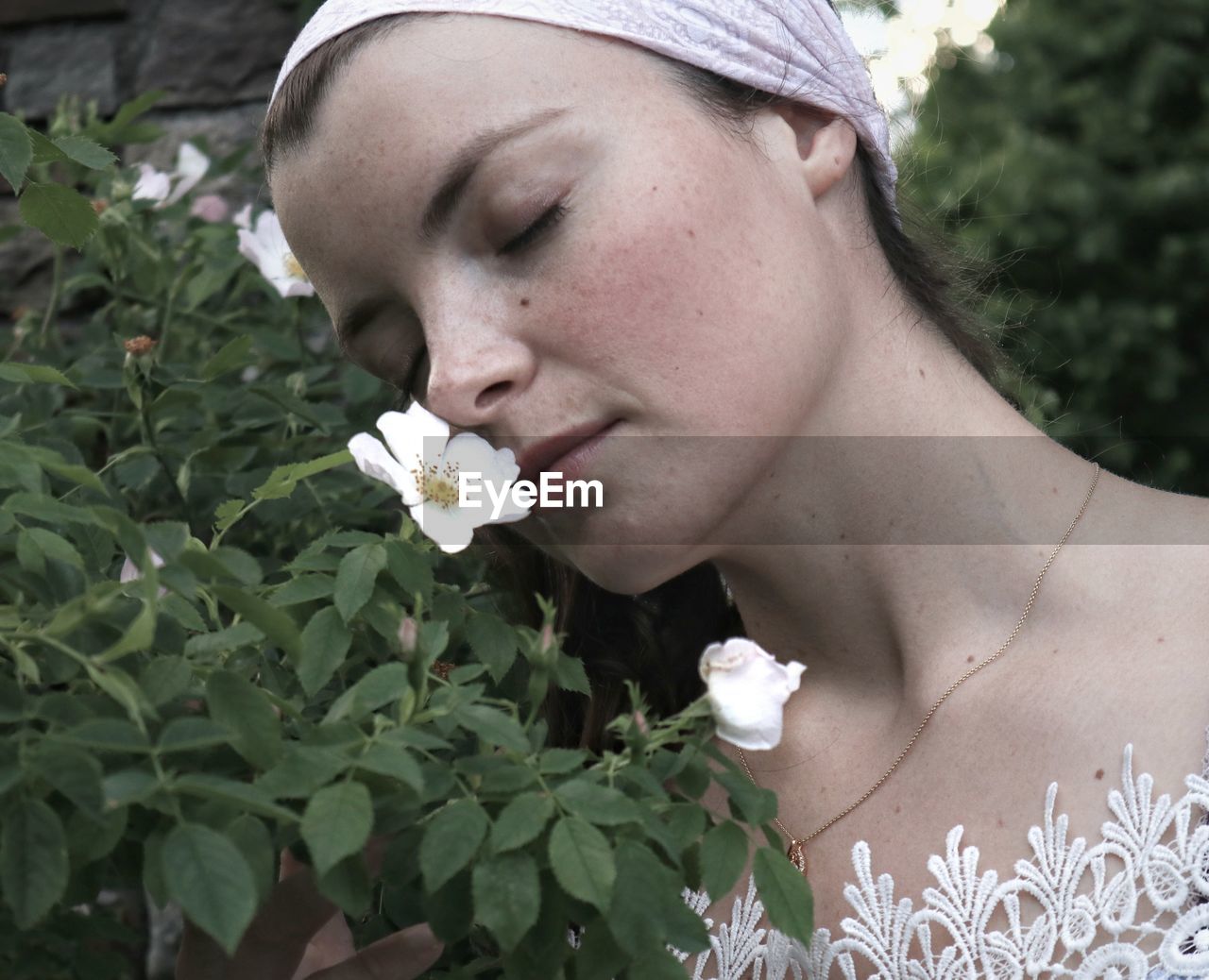 CLOSE-UP OF BEAUTIFUL WOMAN WITH RED FLOWER IN MOUTH