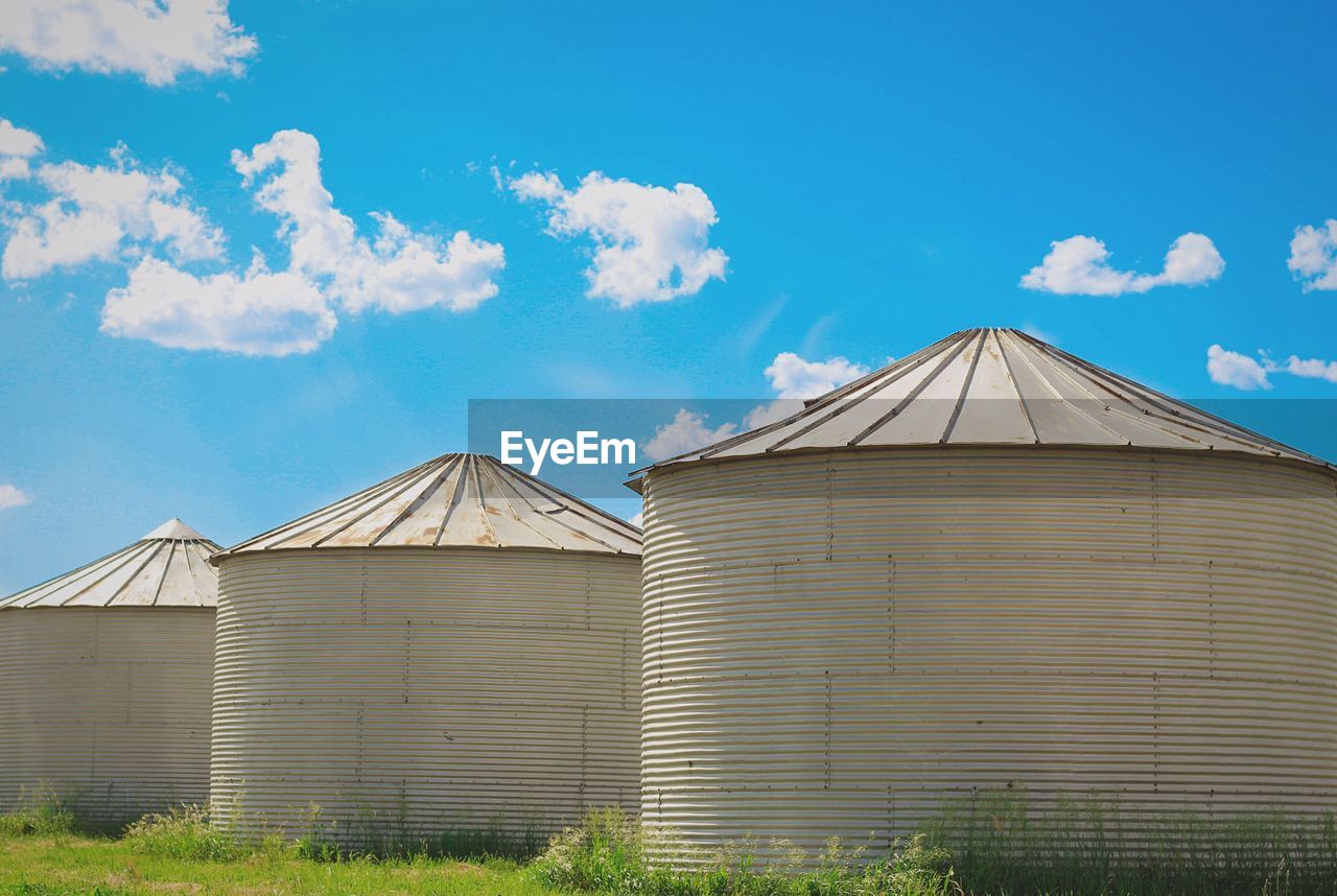 Silos on field against blue sky