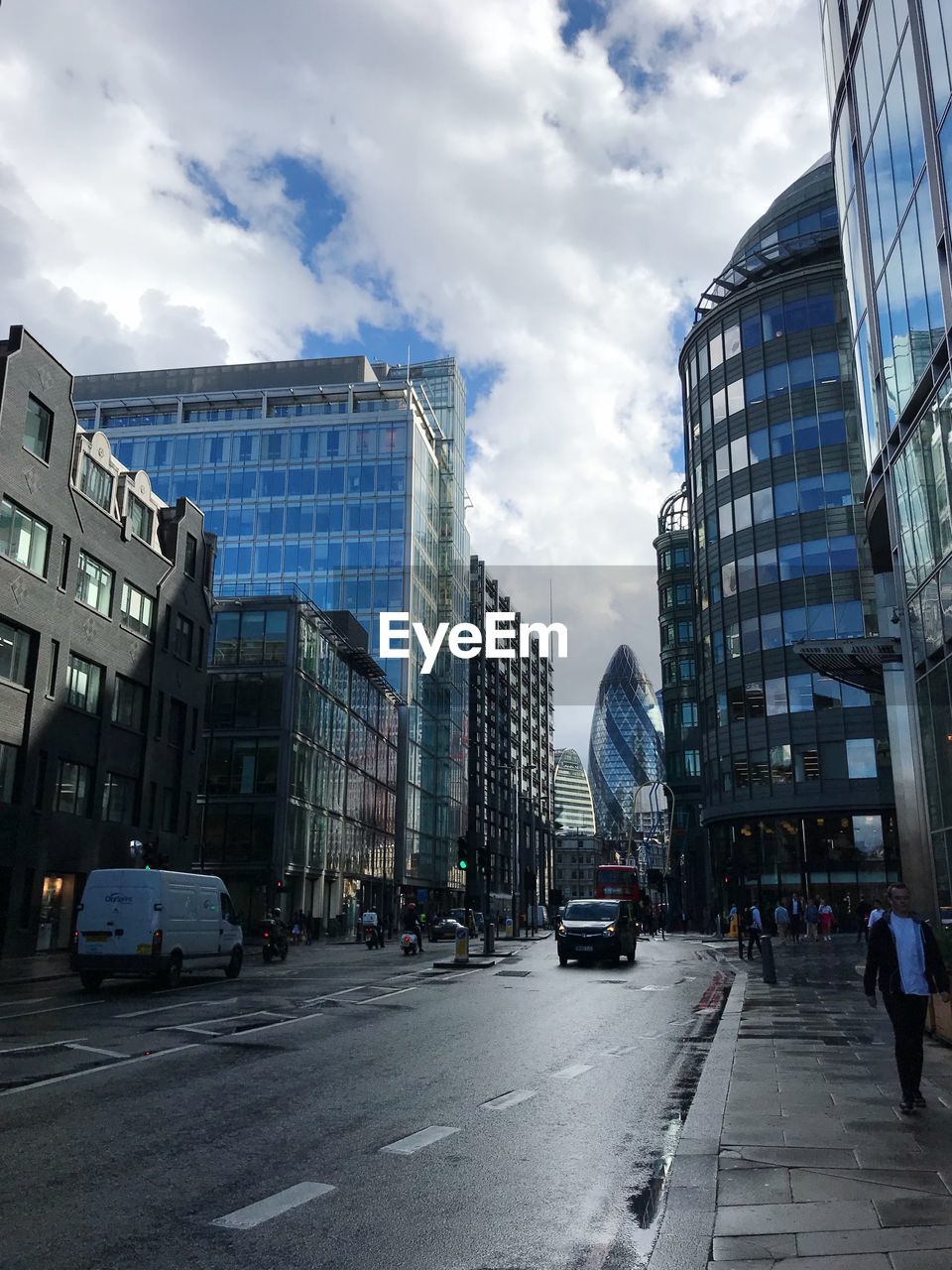 CARS ON ROAD BY BUILDINGS AGAINST SKY IN CITY