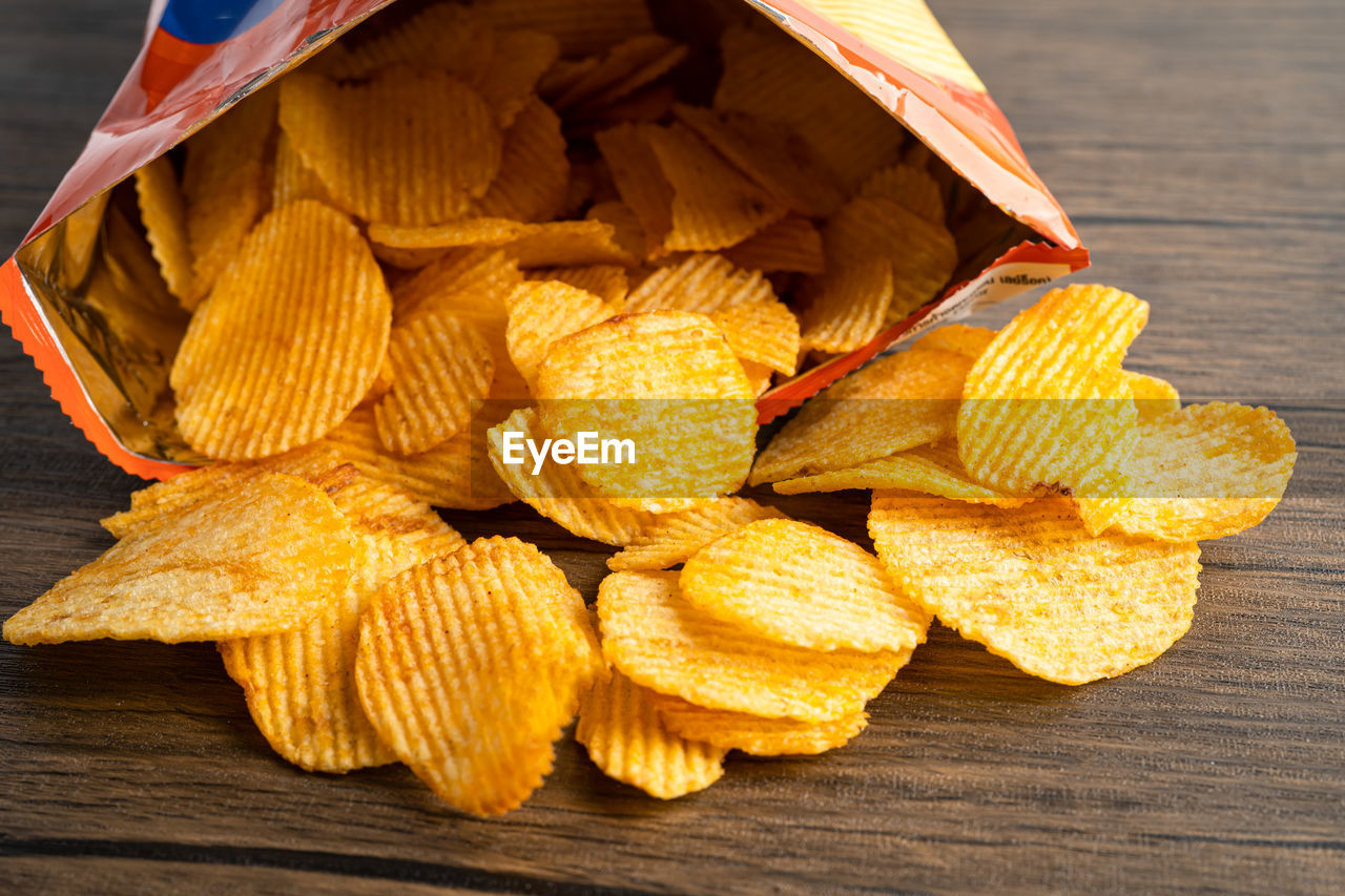 yellow, food, food and drink, junk food, leaf, produce, wood, plant, no people, freshness, close-up, flower, potato chip, large group of objects, healthy eating, table, still life, snack, high angle view, petal