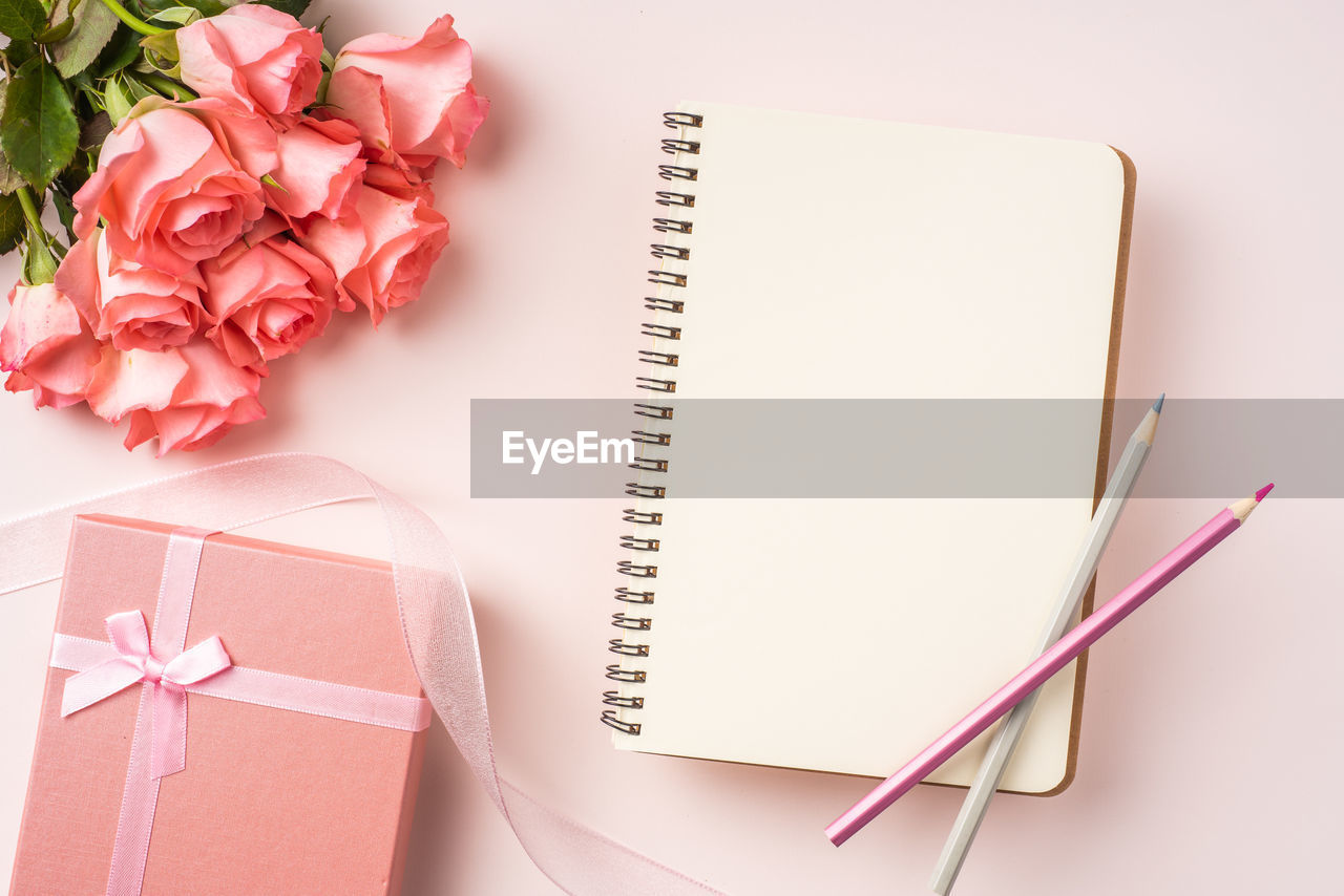 HIGH ANGLE VIEW OF PINK ROSE ON BOOK