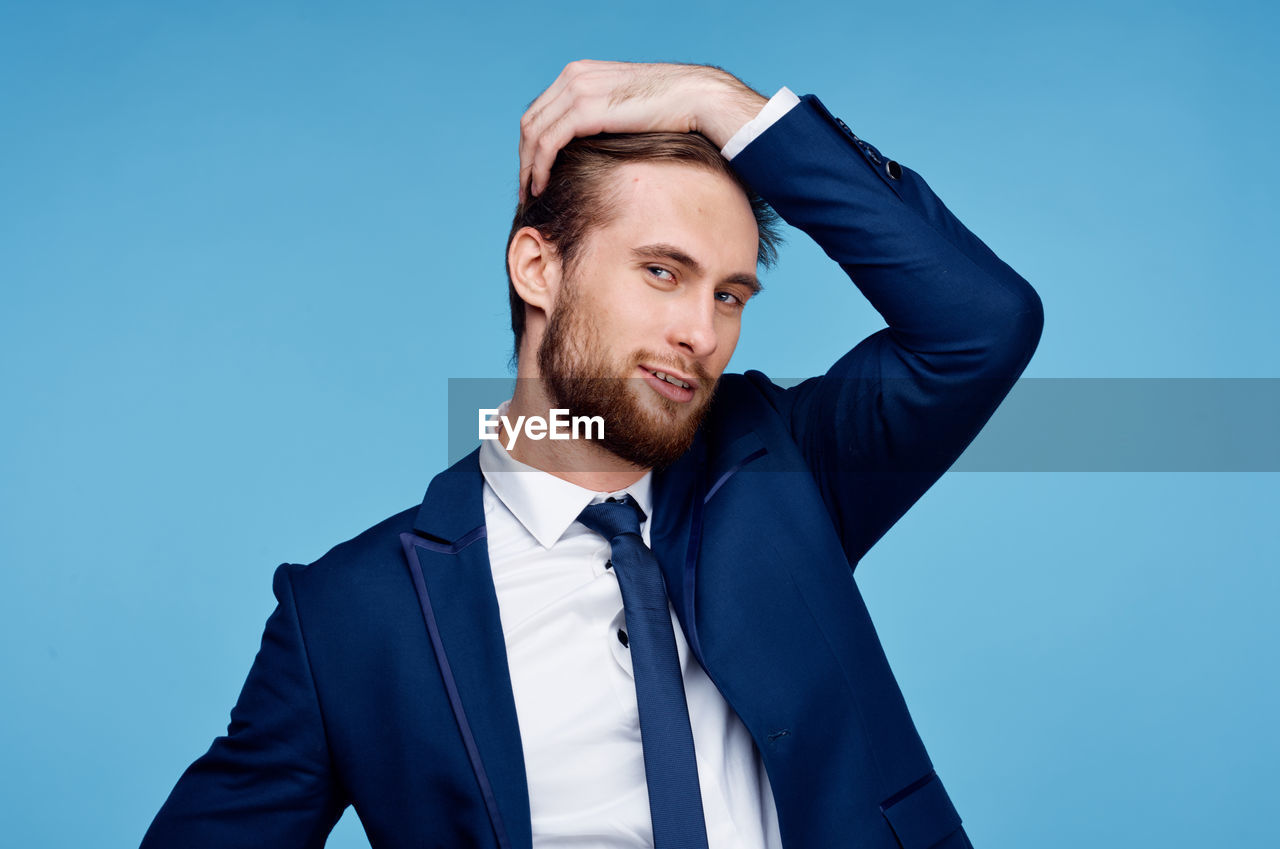 Portrait of young man standing against blue background