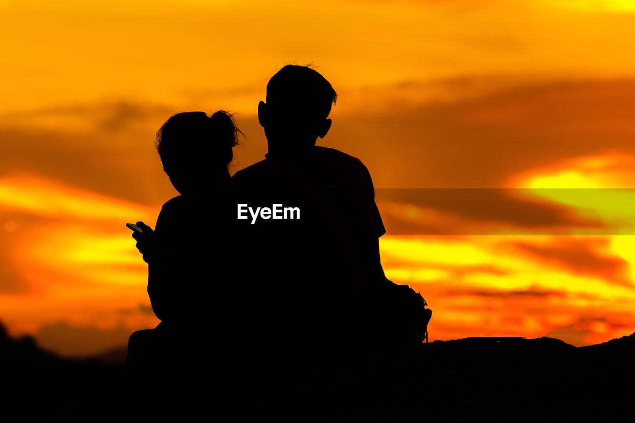 Silhouette couple against orange sky during sunset