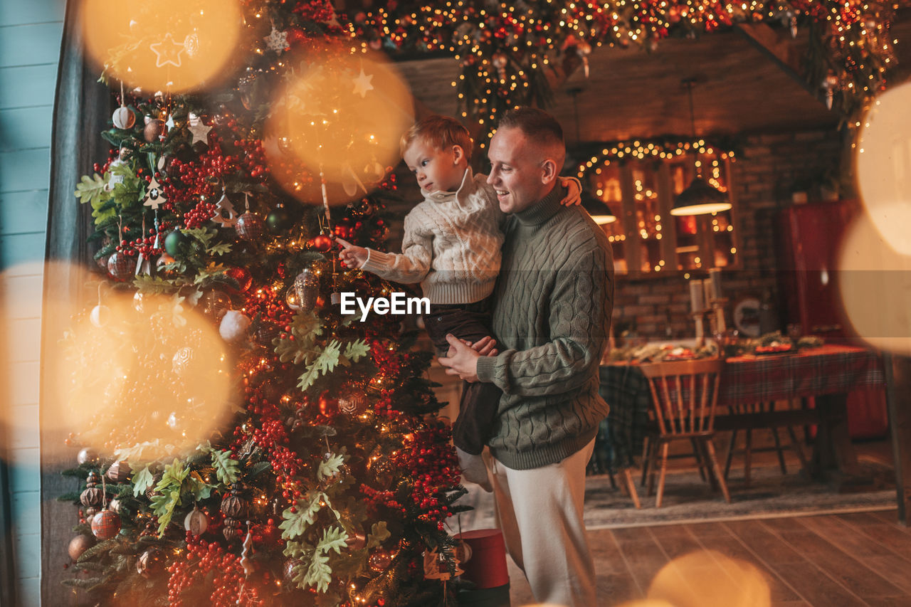 Smile little boy and dad having fun with each other hugs and kisses indoor waiting santa.